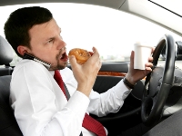 Photograph of a man eating while driving